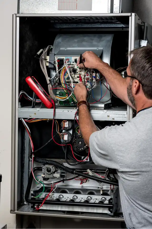 Shane & Son's technician testing the control board inside an open gas furnace